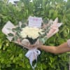 Bouquet of cream roses wrapped in blush paper with a white ribbon