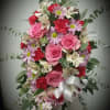 Pink and red mixed flower arrangement with a white ribbon