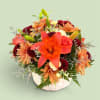 Orange lily and mixed autumn flowers in a white pumpkin vase