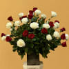 Red and white roses arranged in a tall vase on a pedestal