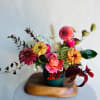 Mixed bouquet of pink, orange, and yellow flowers in a teal vase