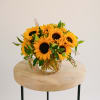 Sunflower arrangement in a clear glass vase on a round table