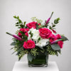 Pink roses and white hydrangeas in a glass vase with greenery