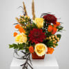 Arrangement of yellow and orange roses with red chrysanthemums in a square vase