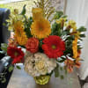Bright mixed bouquet in a yellow vase with red, orange, and white flowers