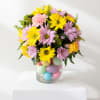 Bouquet of yellow and lavender daisies in a glass vase with pastel eggs