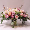 Low pastel arrangement of roses, orchids, and mixed blooms in a white wooden box.