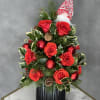 Christmas arrangement with red roses, ornaments, and a Santa hat