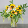 Sunflower and peach rose arrangement in a clear glass vase