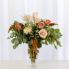 Mixed bouquet of peach and pink roses in a clear glass vase