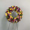 Circular floral wreath on a black stand with pink, yellow, and purple flowers