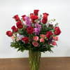 Red roses and pink flowers arranged in a clear glass vase