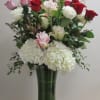 Tall bouquet of red, pink, and white roses with white hydrangeas in a glass vase