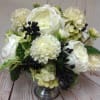 Low arrangement of white roses and mums with dark berries in a silver pedestal bowl