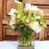White calla lilies and orchids in a clear glass vase
