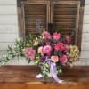 Pink and purple mixed flower arrangement in a white container with ribbon