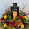 Floral arrangement with a black lantern and candle in the center