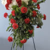 Standing floral spray with white and red carnations on a black easel