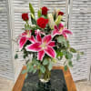 Bouquet of pink lilies and red roses in a clear glass vase