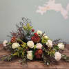 Low floral centerpiece with white roses, red mums, and a black pumpkin