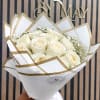 Bouquet of cream roses wrapped in white paper with gold trim