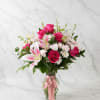 Pink roses and lilies in a glass vase with a pink ribbon