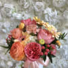 Mixed bouquet of pink, peach, and yellow flowers in a white box with a ribbon