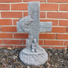 Gray memorial cross sculpture with a fish and kneeling figure
