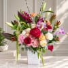 Mixed bouquet in a white vase with roses, orchids, lilies, and pink blooms