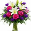 Bouquet of white lilies, pink roses, and purple flowers in a glass vase