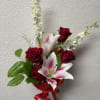 Hand-tied bouquet of red roses and pink lilies with a red ribbon