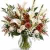White calla lilies and peach roses in a clear glass vase