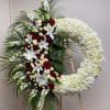 Large floral funeral wreath with red roses, white lilies, and white hydrangeas