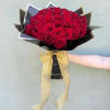 Arm holding a large bouquet of red roses wrapped in black paper with a gold bow.