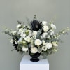 A striking and elegant funeral altar arrangement featuring lush white roses, lisianthus