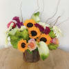 Mixed bouquet with sunflowers, roses, white daisies, and green calla lilies in a wood container