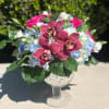 Pink orchids and blue hydrangeas in a glass goblet vase
