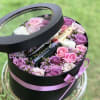 Round black gift box with pink and purple roses and a champagne bottle