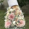Pastel floral arrangement in a hatbox with pink and cream blooms