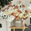 Large bouquet of cream and tan roses with white orchids in a gray vase