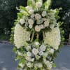 Large white floral standing spray on an easel with roses and lilies