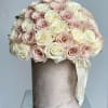 Round bouquet of pale pink and cream roses in a velvet hatbox