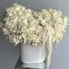 White rose arrangement in a textured white vase with trailing white accents