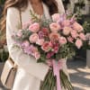 Woman holding a pink and lavender bouquet of roses and lilac flowers