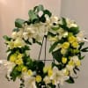 White and yellow floral wreath on a black stand
