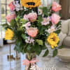 Pink roses and yellow sunflowers in a glass vase with a pink ribbon