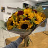 A bold, generous bouquet of large sunflowers and deep red roses with