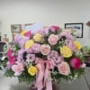 Mixed pink, yellow, and lavender flowers in a basket with a pink ribbon