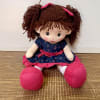 Plush doll with brown yarn hair, blue dress, and pink shoes