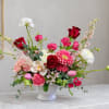 Mixed pink and red flower arrangement in a white vase
